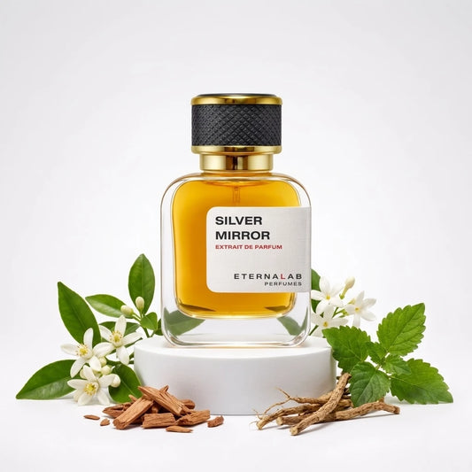 Eterna Lab Silver Mirror perfume bottle surrounded by white neroli blossoms, fresh green leaves, cedarwood chips, and eart...