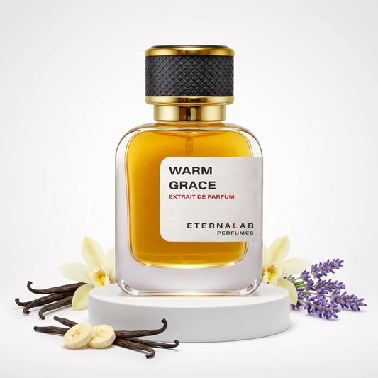 Eterna Lab Warm Grace Extrait de Parfum bottle, surrounded by vanilla pods, a vanilla flower, banana slices, and lavender.